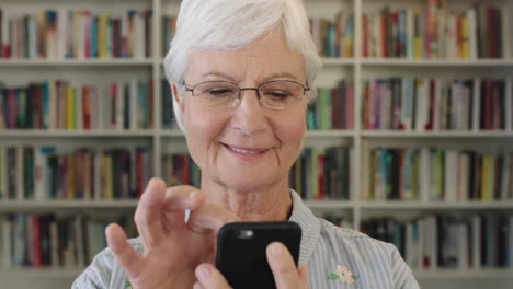Nahaufnahme-Des-Porträts-Einer-Eleganten-Lehrerin-Mittleren-Alters,-Die-Im-Hintergrund-Eines-Bibliotheksbücherregals-SMS-Schreibt-Und-Online-Mit-Smartphone-Mobiltechnologie-Surft