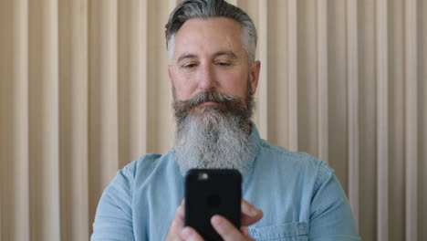 Nahaufnahme-Des-Porträts-Eines-Reifen-Kaukasischen-Mannes-Mit-Stilvollem-Bart,-Der-Mithilfe-Der-Mobilen-Smartphone-Technologie-SMS-Schreibt-Und-Nachdenklich-Und-Fokussiert-Aussieht