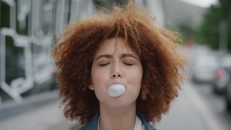 portrait-of-beautiful-young-woman-blowing-bubblegum-sweet-enjoying-playful-fun-cute-female-student-funky-afro-in-urban-city-street-real-people-series