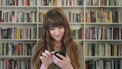 portrait-of-young-friendly-woman-texting-browsing-using-smartphone-cute-librarian-researching-online-in-library-background