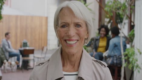 Porträt-Einer-älteren-Frau,-Die-Glücklich-Lächelt-Und-In-Die-Kamera-Blickt-Und-Den-Lebendigen-Urbanen-Lebensstil-Im-Hintergrund-Genießt