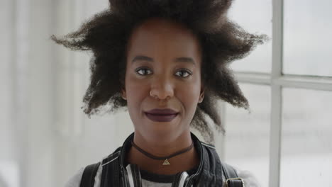 Retrato-De-Una-Mujer-Afroamericana-Segura-De-Sí-Misma-Sonriendo-Tranquilamente-Mirando-La-Cámara-Joven-Estudiante-Con-Un-Peinado-Afro-Funky-En-El-Fondo-Del-Apartamento-Serie-De-Personas-Reales