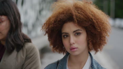 portrait-of-attractive-young-mixed-race-woman-looking-at-camera-pensive-calm-cute-female-student-red-afro-frizzy-hairstyle-in-urban-city-street