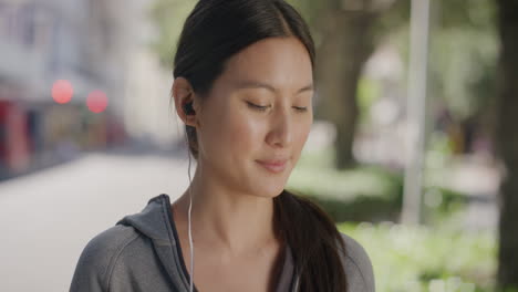 Porträt-Einer-Schönen-Asiatischen-Frau,-Die-Kopfhörer-Aufsetzt-Und-Musik-Hört-Und-Einen-Entspannten,-Sonnigen-Tag-Im-Städtischen-Straßenhintergrund-Genießt