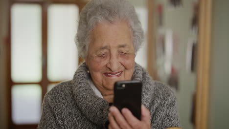 Porträt-Einer-Alten-Frau,-Die-Ihr-Smartphone-Nutzt-Und-Es-Genießt,-Online-Nachrichten-Zu-Lesen.-Ältere-Frau,-Die-Sich-Im-Altersheim-Ein-Video-Auf-Dem-Mobiltelefon-Ansieht-Und-Glücklich-Lacht