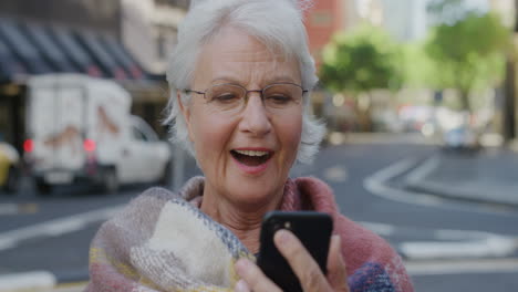 Retrato-De-Una-Anciana-Usando-Mensajes-De-Texto-De-Teléfonos-Inteligentes-Disfrutando-Navegando-Mensajes-En-Línea-En-Tecnología-De-Telefonía-Móvil-Sonriendo-Feliz-En-La-Calle-De-La-Ciudad-Serie-De-Personas-Reales