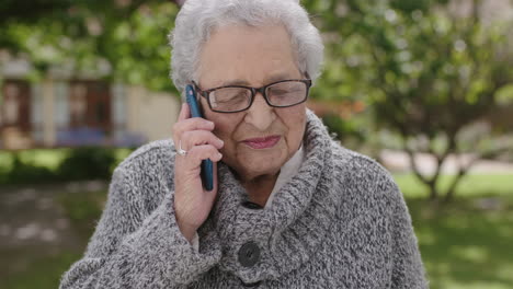 Retrato-De-Una-Anciana-Mujer-De-Raza-Mixta-Hablando-Por-Teléfono-Disfrutando-Charlando-En-El-Soleado-Jardín