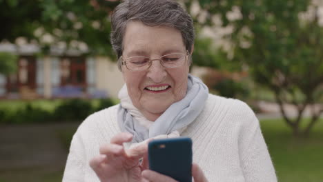 portrait-of-elegant-elderly-woman-using-smartphone-in-garden-outdoors-texting-browsing