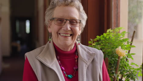 portrait-of-happy-elderly-woman-standing-by-window-smiling-cheerful-enjoying-retirement
