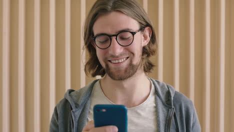 Nahaufnahme-Des-Porträts-Eines-Süßen-Geekigen-Mannes-Mit-Brille,-Der-Lächelt-Und-Das-Surfen-Per-SMS-Mit-Smartphone-Mobiltechnologie-Im-Innenbereich-Genießt