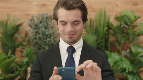 attractive-young-business-man-portrait-of-sales-person-wearing-suit-texting-browsing-using-smartphone-mobile-technology-enjoying-networking