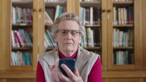 Porträt-Einer-älteren-Kaukasischen-Frau-In-Der-Bibliothek,-Die-Mit-Der-Smartphone-Messaging-App-SMS-Schreibt-Und-Ernsthaft-Nachdenklich-Ist