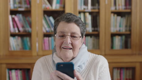 Porträt-Einer-älteren-Frau-In-Der-Bibliothek,-Die-Mit-Der-Smartphone-Messaging-App-SMS-Schreibt-Und-Glücklich-Lächelt