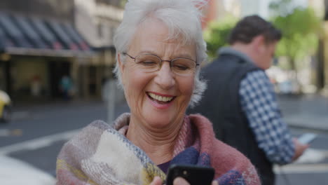 Retrato-De-Una-Anciana-Usando-Mensajes-De-Texto-De-Teléfonos-Inteligentes-Disfrutando-Navegando-Mensajes-En-Línea-En-Tecnología-De-Telefonía-Móvil-Sonriendo-Feliz-En-La-Calle-De-La-Ciudad-Serie-De-Personas-Reales