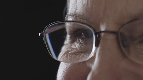 Nahaufnahme-Eines-Blinzelnden-Auges-Einer-Alten-Frau-Mit-Brille,-Isoliert-Auf-Schwarzem-Hintergrund,-Kopierraum
