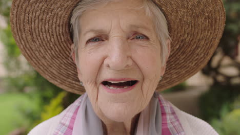 Primer-Plano-Retrato-De-Una-Anciana-Mirando-La-Cámara-Sonriendo-Feliz-Usando-Sombrero-Disfrutando-Del-Soleado-Jardín-Al-Aire-Libre