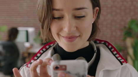 close-up-portrait-of-stylish-young-caucasian-woman-smiling-relaxed-texting-browsing-using-smartphone-social-media-app-in-modern-office-workspace