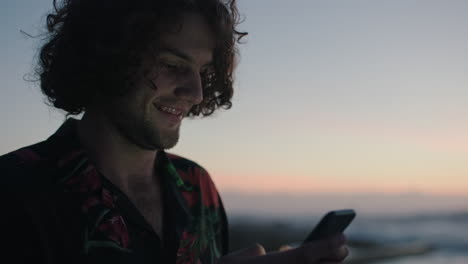 young-man-using-phone-texting-by-seaside-waiting-sunset-sunrise
