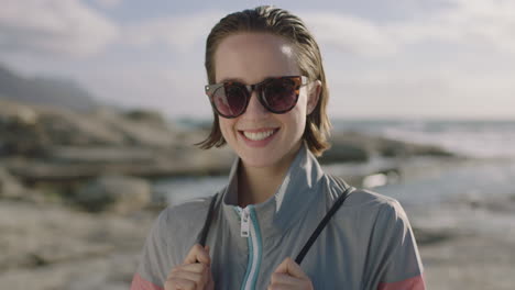Porträt-Einer-Attraktiven,-Selbstbewussten-Frau,-Die-Am-Strand-Lächelt-Und-Eine-Sonnenbrille-Trägt