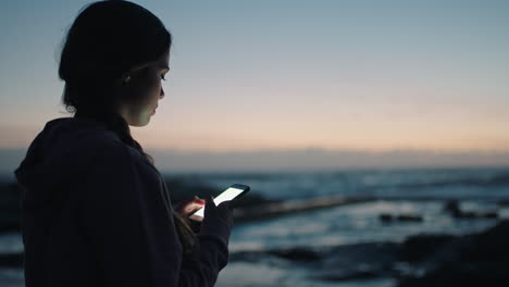 young-woman-texting-by-seaside-beach-waiting-sunset-sunrise