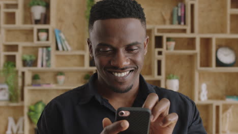 close-up-portrait-of-charming-young-masculine-african-american-man-enjoying-texting-browsing-using-phone