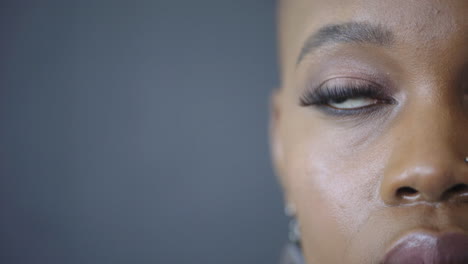 Nahaufnahme-Porträt-Einer-Attraktiven-Afroamerikanischen-Frau,-Die-In-Die-Kamera-Blickt,-Nachdenkliche,-Kontemplative-Schwarze-Weibliche-Schönheit-Auf-Blauem-Hintergrund,-Halbes-Gesicht