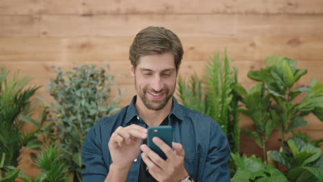 attractive-young-man-portrait-of-handsome-caucasian-guy-happy-enjoying-texting-browsing-using-smartphone-mobile-technology-app-in-plants-background