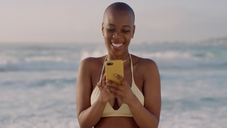 Porträt-Einer-Schönen-Afroamerikanischen-Frau,-Die-Ihr-Smartphone-Nutzt,-Um-Im-Internet-Zu-Surfen-Und-Einen-Sexy-Bikini-Am-Warmen,-Sonnigen-Strand-Zu-Tragen,-Der-Den-Sommer-In-Zeitlupe-Genießt
