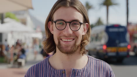 portrait-of-handsome-young-man-geek-wearing-glasses-laughing-enjoying-summer-vacation-sunny-outdoors-looking-calm-on-busy-urban-beachfront-real-people-series