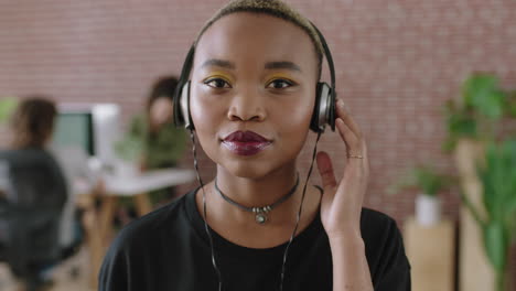 Porträt-Einer-Trendigen-Jungen-Afroamerikanischen-Frau-Mit-Kopfhörern,-Die-In-Einem-Modernen-Büroarbeitsplatz-Musik-Hört