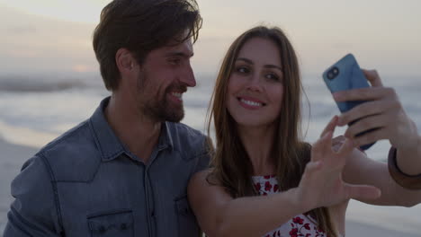 Junges-Glückliches-Kaukasisches-Paar,-Das-Mit-Dem-Smartphone-Fotografiert-Und-Gemeinsam-Den-Romantischen-Sonnenuntergang-Am-Strand-In-Zeitlupe-Genießt