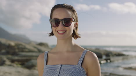 Porträt-Einer-Attraktiven-Frau,-Die-Entspannt-Am-Strand-Lächelt-Und-Eine-Sonnenbrille-Trägt