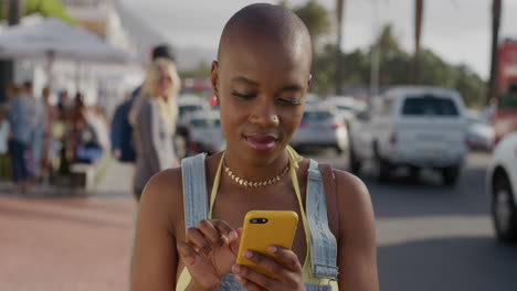 portrait-of-attractive-african-american-woman-using-smartphone-enjoying-texting-sending-sms-messages-sharing-vacation-experience-in-sunny-urban-street