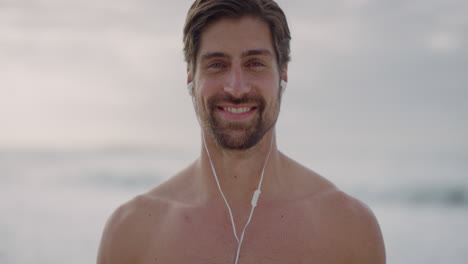 Porträt-Eines-Muskulösen-Mannes-Mit-Nacktem-Oberkörper,-Der-Lächelt-Und-Das-Musikhören-Mit-Kopfhörern-Am-Schönen-Strand-Am-Meer-Genießt.-Gesunder-Lebensstil-Eines-Kaukasischen-Mannes
