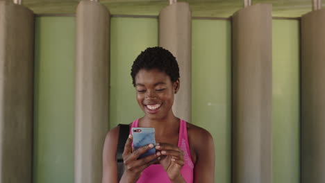 Porträt-Einer-Jungen-Afroamerikanischen-Frau,-Die-Lächelt-Und-Ihr-Telefon-Nutzt,-Um-In-Sozialen-Medien-Zu-Surfen