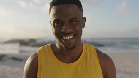 Porträt-Eines-Fitten,-Gutaussehenden-Afroamerikanischen-Mannes,-Der-Selbstbewusst-Am-Strand-Lächelt-Und-Eine-Gelbe-Weste-Trägt