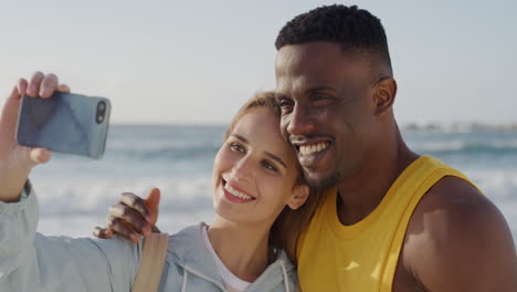 portrait-of-young-multi-ethnic-couple-taking-selfie-photo-using-smartphone-camera-on-beach-smiling-enjoying-romantic-vacation-together-at-warm-summer-seaside