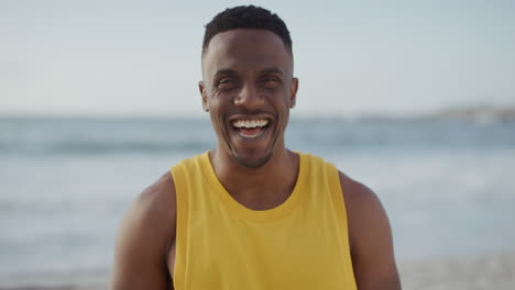 Porträt-Eines-Fitten,-Gutaussehenden-Afroamerikanischen-Mannes,-Der-Selbstbewusst-Am-Strand-Lacht-Und-Eine-Gelbe-Weste-Trägt