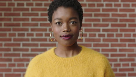 Porträt-Einer-Stilvollen-Afroamerikanischen-Frau-Im-Gelben-Trikot,-Die-Selbstbewusst-Auf-Einem-Backsteinmauerhintergrund-Aussieht