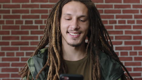 portrait-of-attractive-mixed-race-man-with-dreadlocks-smiling-happy-using-smartphone