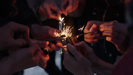 group-of-friends-close-up-hands-holding-lighting-sparklers-celebrating-new-years-eve-party