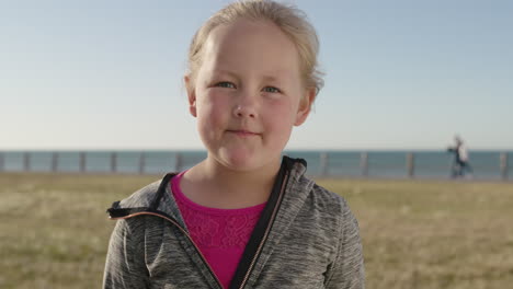 close-up-portrait-of-cute-little-blonde-girl-looking-pensive-serious-at-camera-carefree-child-seaside-park