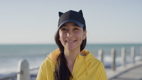 portrait-mixed-race-teenage-girl-smiling-cheerful-looking-at-camera-wearing-yellow-jacket-enjoying-sunny-seaside-beach