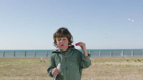 Porträt-Eines-Süßen-Kaukasischen-Jungen,-Der-Seifenblasen-Bläst-Und-Einen-Schönen-Tag-Am-Strand-Genießt