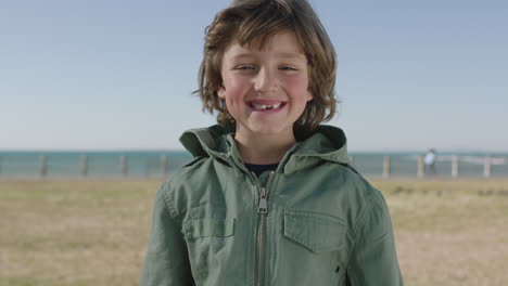 portrait-of-cute-happy-boy-smiling-cheerful-at-camera-enjoying-fun-day-on-seaside-beach-park
