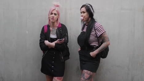 Porträt-Zweier-Attraktiver-Junger-Punk-Frauen,-Die-Gelangweilt-Und-Entspannt-Warten-Und-Kaugummi-Blasen-Und-Einen-Alternativen-Modestil-Tragen,-Der-Ein-Tattoo-Im-Urbanen-Lebensstil-In-Zeitlupe-Trägt