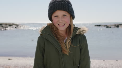 Porträt-Eines-Mädchens-Am-Strand,-Das-Glücklich-Lächelt-Und-Warm-Gekleidet-Ist-Und-Eine-Mütze-Und-Einen-Mantel-Trägt