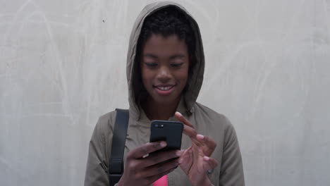 Nahaufnahme-Eines-Porträts-Einer-Jungen-Afroamerikanischen-Frau,-Die-Ihr-Smartphone-Nutzt,-SMS-Schreibt-Und-Im-Internet-Surft-Und-Die-Online-Kommunikation-Auf-Dem-Mobiltelefon-Mit-Kapuze-In-Zeitlupe-Genießt