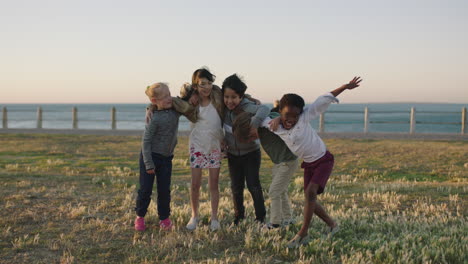 Fröhliche,-Fröhliche-Kinder-Porträt-Einer-Aufgeregten-Kindergruppe,-Die-Sich-Umarmt-Und-Feiert-Und-Den-Strandspaß-Am-Meer-Bei-Sonnenuntergang-Genießt