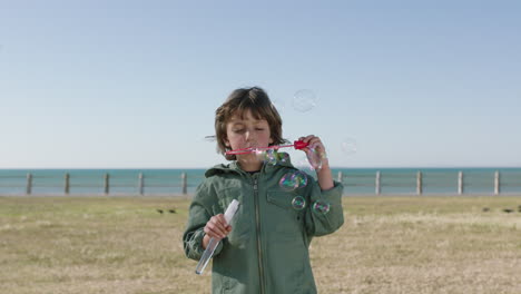 Porträt-Eines-Süßen-Kaukasischen-Jungen,-Der-Seifenblasen-Bläst-Und-Einen-Schönen-Tag-Am-Strand-Genießt